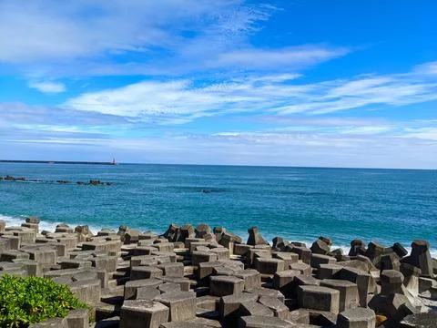 A beach filled with tetrapod facing the Pacific Ocean with a lighthouse in sight Foto stock