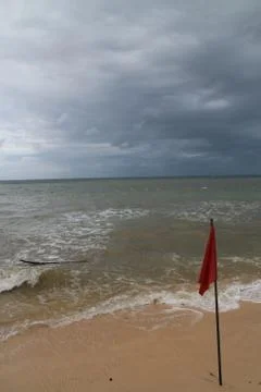 Beach with flag, waves, cloudy sky 스톡 사진