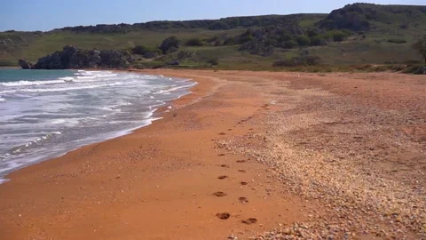 Beach with footprints in the sand, sea waves calmly touch the shore Stock Footage 142399211