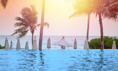 Beach front with water pool ,coconut tree,umbrella,bush,blur swimmer on sun.. Stock-Fotos