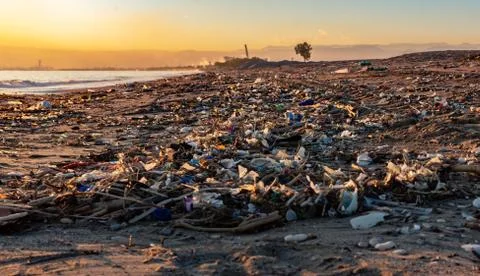 A beach full of garbage at sunset Stock Photos