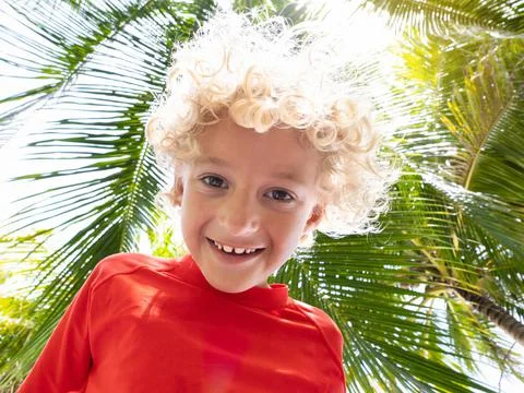 Beach fun. Curly boy under palm tree. Stock Photos
