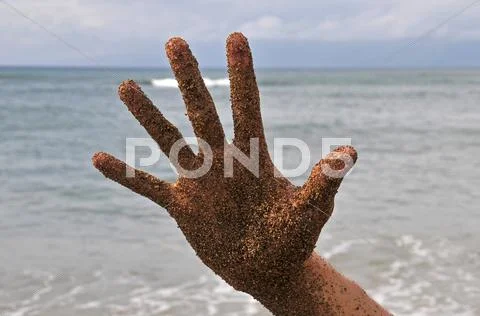 Beach fun with a wet hand with sand on it giving a thumbs up. ocean beach wav Stock Photos