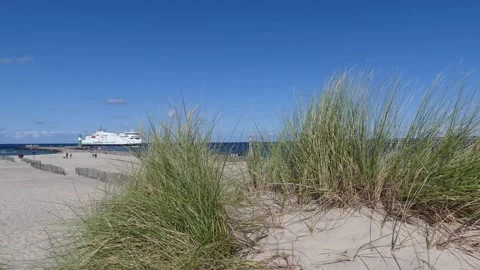 Beach grass with white sand in summer - blue sky, lighthouse, ship in background Stock Footage 139214423