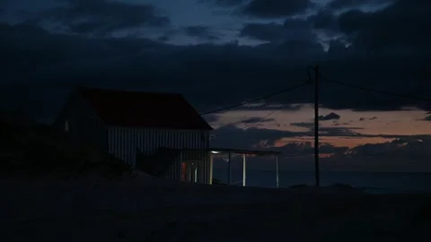 Beach hut and power lines beneath storm clouds Vidéo 328254038