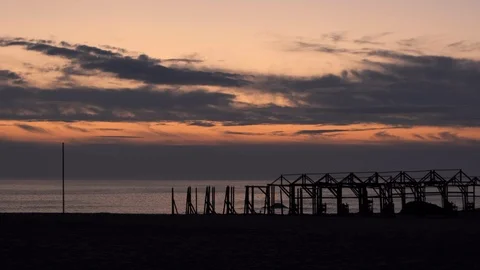 Beach hut frames in silhouette at dusk, against vivid sunset sky. Pan up Stock Footage 116358628