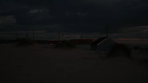 Beach huts and dunes beneath heavy evening clouds Video stock 328253630
