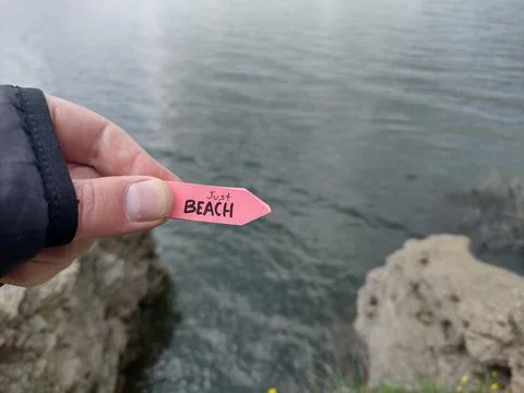Beach idea. A hand holds a pointer with the inscription beach. Stock Photos