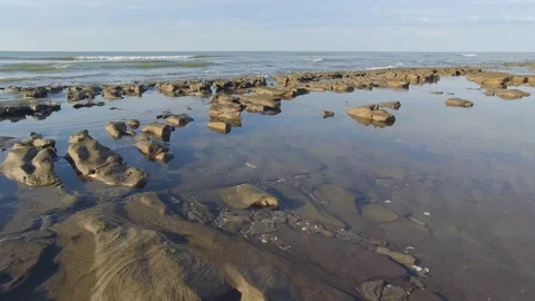 Beach landscape featuring a rocky shoreline meeting the ocean Stock Footage 302829652