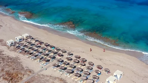 Beach lined with thatch parasols and straw umbrellas on greek island in Greece Stock Footage 328007573