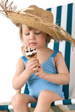 Beach - little girl on deck-chair with hat and ice-cream Stock Photos
