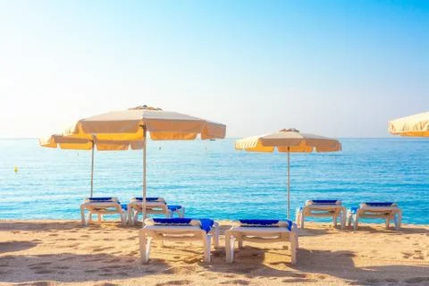 Beach in Lloret de Mar, Spain. Umbrellas and deckchairs on sandy beach in spa Stock Photos