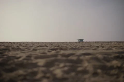 Beach, low angle across the sand, clear skies, lifeguard tower, rack focus LA Stock Footage 296704087