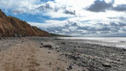 Beach at low tide with dark cliffs Stock Photos