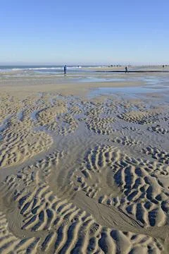 Beach at low tide with wave like pattern current ripples blue sky North Sea Stock Photos