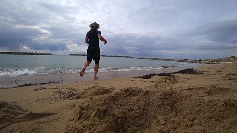 By the beach with a man running in the water Stock Footage 190590302