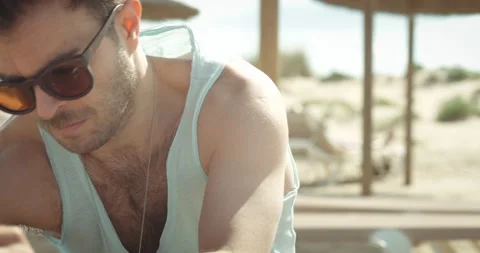 Beach: Man seated takes things out of his backpack Video stock 205022714