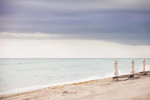 Beach in Miami, FL. Folded umbrellas on the sand beach at the ocean.  Stock Photos