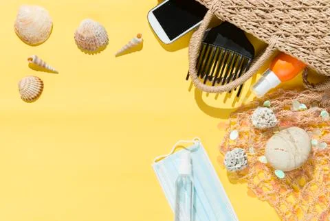 Beach objects, face mask and hydro alcoholic gel on yellow background. Stock Photos