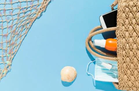 Beach objects, face mask and hydro alcoholic gel on blue background. Stock Photos