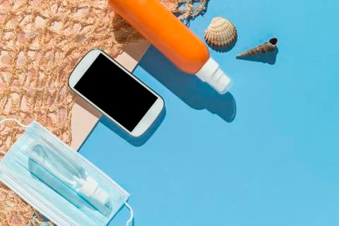 Beach objects, face mask and hydro alcoholic gel on pink and blue background. Stock Photos