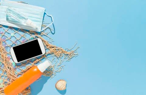 Beach objects, face mask and hydro alcoholic gel on blue background. Stock Photos