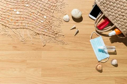 Beach objects, face mask and hydro alcoholic gel on parquet flooring. Stock Photos