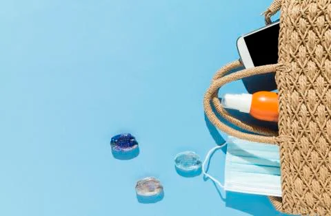 Beach objects, face mask and hydro alcoholic gel on blue background. Stock Photos