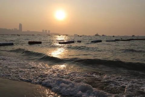 Beach Ocean Waves Sunset Glow With Distant City Skyline Stock Photos