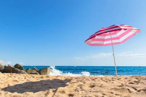Beach with parasol Empty beach with waves, sea and striped pink parasol Co... Foto stock