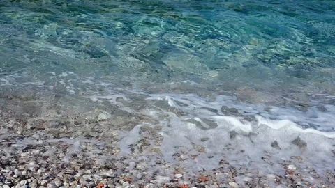 Beach pebbles on shore and rolling turquoise sea waves splashing Stock Footage 116539075