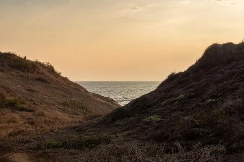 A beach peeks between two mountains during sunset. colorful horizon. Foto stock