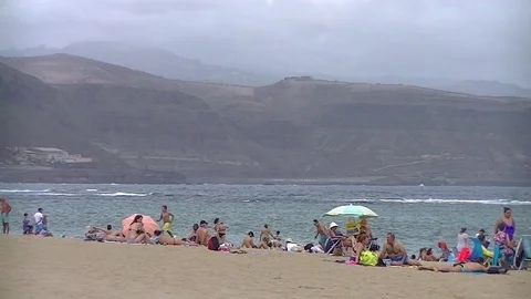 Beach with people in a cloudy day Stockbeeldmateriaal 80041895
