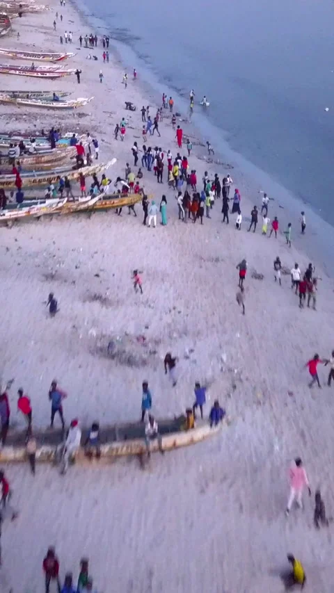 Beach with people running and dancing around senegalese traditional fishing boat Stock Footage 230671699