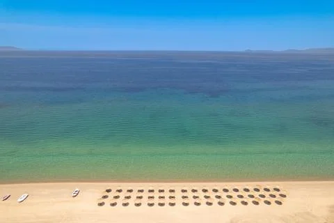 Beach perspective view of even rows of umbrellas and the surface of the sea as Stock Photos