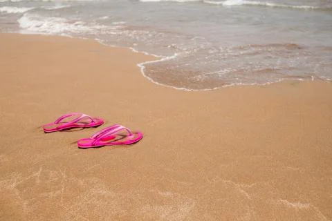 Beach pink flip-flops on a light sand. Texture of light sand. The concept of Stock Photos