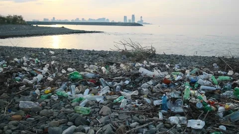 Beach plastic pollution. Plastic bottles and other trash on sea stone beach Stock Footage 226142102