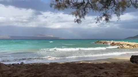 A beach with a rainbow and a stormy sky. Rainbow over the stormy sea after rain  Stock Footage 265286914