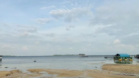 The beach is receding with the blue sky so that the kelong house appears Stockbeeldmateriaal 232321842