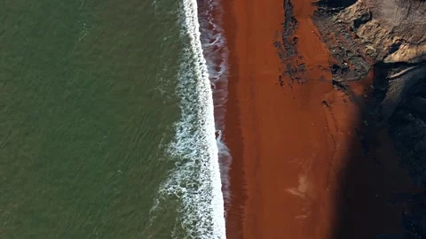 A beach with a red wall and a green ocean Stock Footage 303987394