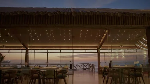 Beach Restaurant at Sunset, Interior Lighting with Ocean View Through Windows 6K Stock Footage 324924499