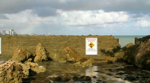 Beach rocks warning sign rainbow 1 Stock Footage 8984285
