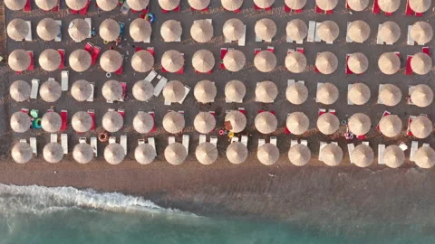 Beach with rows of thatch umbrellas - tiki straw parasols by the sea Stock Footage 212990077