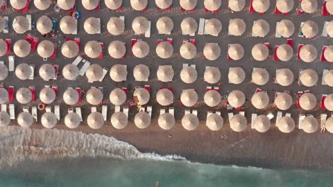Beach with rows of thatch umbrellas - tiki straw parasols by the sea Stock Footage 213000777