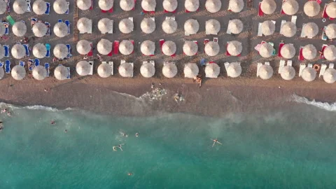 Beach with rows of thatch umbrellas - tiki straw parasols by the sea Stock Footage 213044891