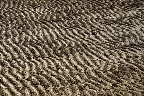 Beach sand texture in hard light generated from wave tidal Stock Photos