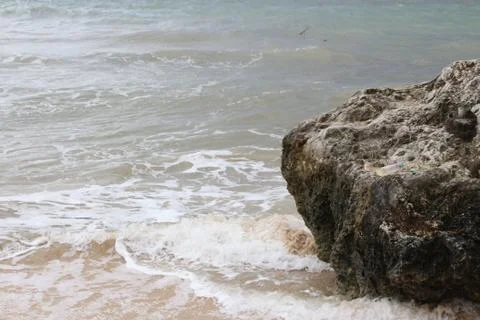 Beach with sand, waves, sky and rock 스톡 사진