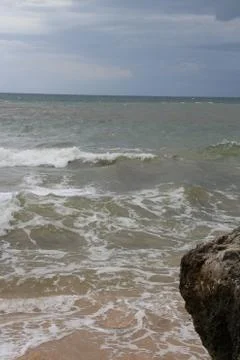 Beach with sand, waves, sky and rock 스톡 사진