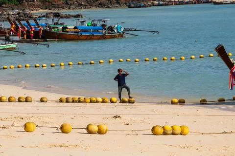 A Beach Scene Featuring a boy looking on among Colourful Boats by the Shoreline Stock Photos