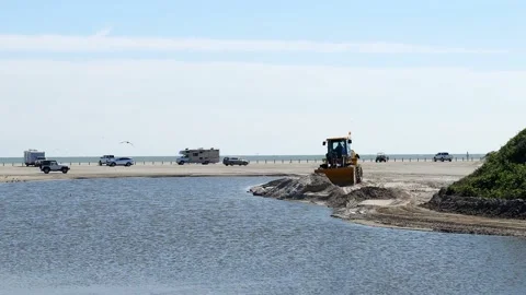 Beach scene with a front end loader and vehicles on the sand by ocean. Stock Footage 138533279